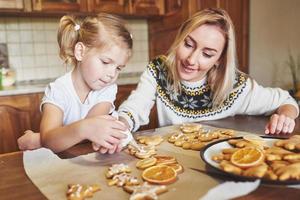 lugar de trabajo de confitería con manos de mujer decorando galletas de navidad. panadería casera, dulces soleados, vacaciones de invierno. foto