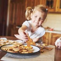 Confectionery workplace with women's hands decorating Christmas cookies. Home bakery, sunny sweet, winter holidays. photo