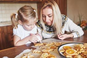 Confectionery workplace with women's hands decorating Christmas cookies. Home bakery, sunny sweet, winter holidays. photo