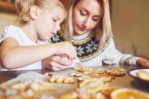 Confectionery workplace with women's hands decorating Christmas cookies. Home bakery, sunny sweet, winter holidays. photo