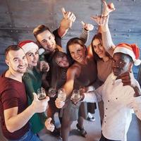 New Year is coming. Group of cheerful young multiethnic people in Santa hats on the party, posing emotional lifestyle people concept photo