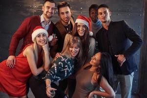 el nuevo año está llegando. Grupo de alegres jóvenes multiétnicos con gorro de Papá Noel en la fiesta, posando concepto de gente de estilo de vida emocional foto