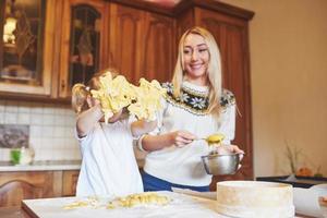 Happy daughter and mom in the kitchen bake cookies photo