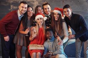 New Year is coming. Group of cheerful young multiethnic people in Santa hats on the party, posing emotional lifestyle people concept photo