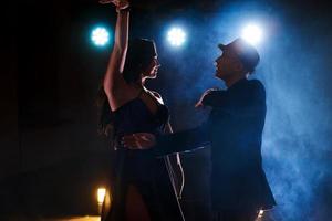 Skillful dancers performing in the dark room under the concert light and smoke. Sensual couple performing an artistic and emotional contemporary dance photo