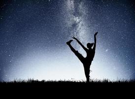 una chica deportiva al amanecer se dedica al yoga. clases de gimnasia en el cielo estrellado foto