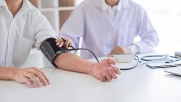 médico que mide y controla la presión arterial del paciente en el hospital, la atención médica y el concepto de medicina. foto