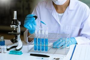 Scientist wear lab coat and protective wear are working with research or doing investigations with test tubes in experiment, Laboratory and development concept