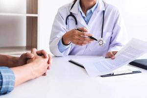 patient listening intently to a male doctor explaining patient symptoms or asking a question as they discuss paperwork together in a consultation photo