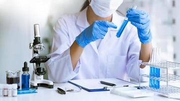 scientists researching in laboratory in white lab coat, gloves analysing, looking at test tubes sample, biotechnology concept photo