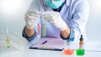 scientists researching in laboratory in white lab coat, gloves analysing, looking at test tubes sample, biotechnology concept photo