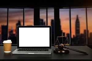 Workspace of lawyer with laptop blank white screen and law wooden gavel, and brass scale of judge. photo