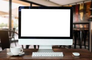 monitor de computadora, teclado, teléfono inteligente de taza de café, tableta y mouse con pantalla en blanco o en blanco aislado está en la mesa de trabajo en la cafetería foto