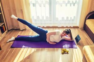 Young attractive woman in sports clothing doing workout at home photo