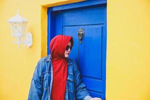 mujer musulmana abre la puerta de madera azul en la colorida casa amarilla clásica foto