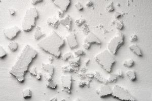 Broken pieces of white styrofoam on the sheet of white styrofoam photo