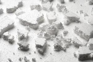 Broken pieces of white styrofoam on the sheet of white styrofoam photo