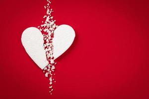 Background with white broken styrofoam heart on a red backdrop photo