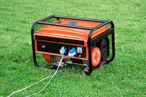 generador eléctrico portátil con cables eléctricos conectados en la hierba verde en verano foto