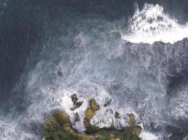 Top down aerial view of giant ocean waves crashing and foaming in coral beach photo