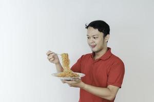 Portrait of happy Young Asian man enjoys noodles with tongue out. Eating lunch concept. photo
