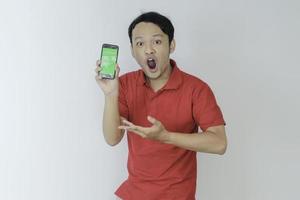 Wow face of Young asian man smiling when showing green screen of smartphone in studio background photo