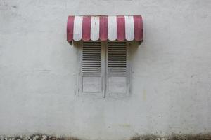 viejo toldo parasol sobre una vieja ventana blanca cerrada foto