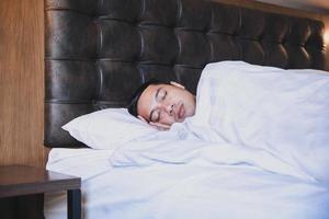 Asian man sleeping tightly on his comfortable bed at home photo