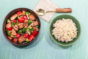 Rice dish chicken fried and vegetable broccoli pepper on green table photo