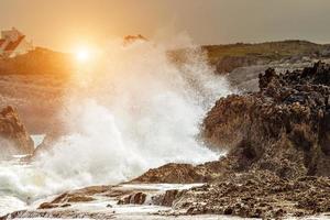 Waves crashing at sunset on the rocks of a beach in Cantabria, Spain. Horizontal image. photo