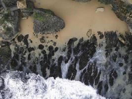 Top down aerial view of giant ocean waves crashing and foaming in coral beach photo