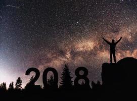 silueta joven feliz por el fondo de año nuevo 2018 de la galaxia de la vía láctea en una estrella brillante tono de cielo oscuro foto