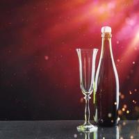 Glass and bottle of champagne on a dark background photo