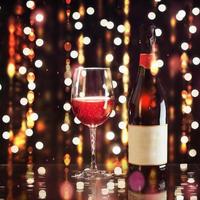 Red wine glass with bottle on background lights. Happy new year