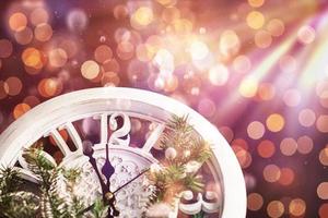 feliz año nuevo a la medianoche de 2018, viejo reloj de madera con luces navideñas y ramas de abeto foto