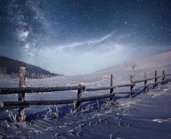 Winter landscape. Mountain village in the Ukrainian Carpathians. Vibrant night sky with stars and nebula and galaxy. Deep sky astrophoto