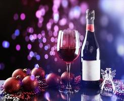 Christmas and New Year. Festive decorations, bottle of red wine and glass on the dark background. Happy New Year and Christmas. Bokeh light soft effect photo