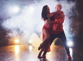 hábiles bailarines actuando en la habitación oscura bajo la luz y el humo del concierto. pareja sensual realizando una danza contemporánea artística y emocional foto