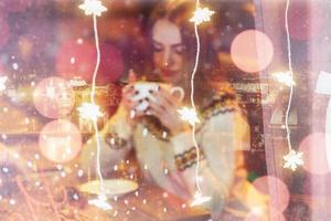 Young beautiful woman sitting in cafe, drinking coffee. Christmas, new year, winter holidays concept double exposure, night city photo