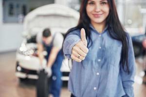 Mechanic holding a tire tire at the repair garage. The woman approves the work done by the client photo