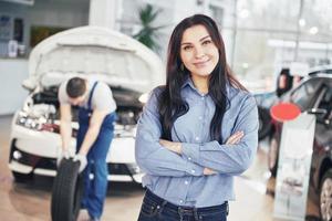 Mechanic holding a tire tire at the repair garage. The client woman waits for the job photo