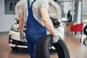 Mechanic holding a tire tire at the repair garage. replacement of winter and summer tires photo