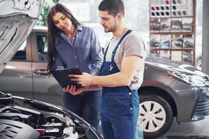 A man mechanic and woman customer discussing repairs done to her vehicle photo