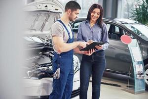 Mechanic showing a paper in a clipboard to a woman in a garage photo