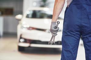 Hands of car mechanic with wrench in garage photo