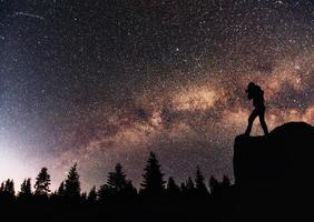 fotógrafo de naturaleza de silueta con cámara digital, fondo de la galaxia de la vía láctea en un tono de cielo oscuro de estrella brillante foto