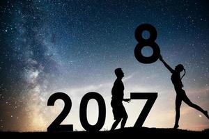 Silhouette young girl and guy. Happy 2018 new year. Background of the Milky Way galaxy on a bright star dark sky tone. Concept change year 2017 to 2018 photo