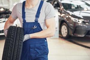 Mechanic holding a tire tire at the repair garage. replacement of winter and summer tires photo