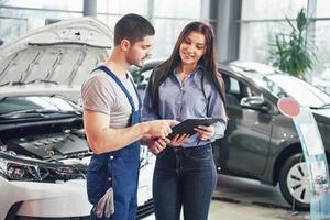 A man mechanic and woman customer discussing repairs done to her vehicle photo