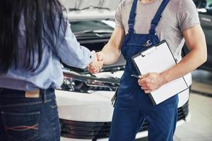 husband car mechanic and woman customer make an agreement on the repair of the car photo